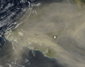 Satelitní snímek družice Terra ze 7. prosince 2022.  Nad mračnem prachu ze Sahary, který zahalil Sicílii, vystupuje zasněžený vrcholek Etny. Menší erupce, která je u této sopky pozorována od 27. listopadu, není na snímku vidět.